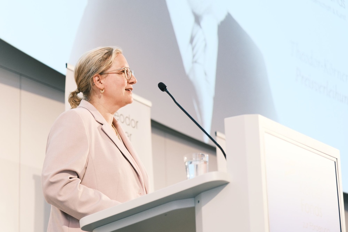 Eine Frau steht auf einer B&uuml;hne und spricht in ein Mikrophon. &copy; TKF / Christopher Glanzl